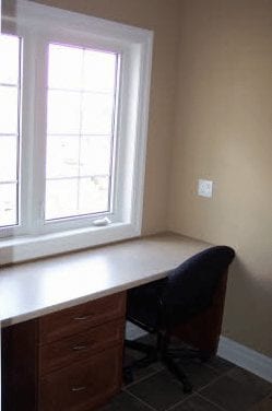 Desk and office chair set up in front of a panel window