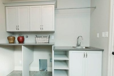An empty laundry room with sink and space for washer and dryer